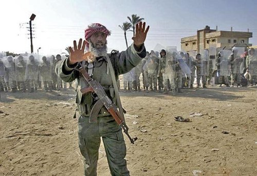 Zum Foto: Ein Hamas-Terrorist versucht, Bewohner des Gazastreifens vom Sturm auf die Grenze zu Ägypten abzuhalten, die von ägyptischen Polizisten (im Bildhintergrund) gesichert wird. Rafah, Januar 2008.